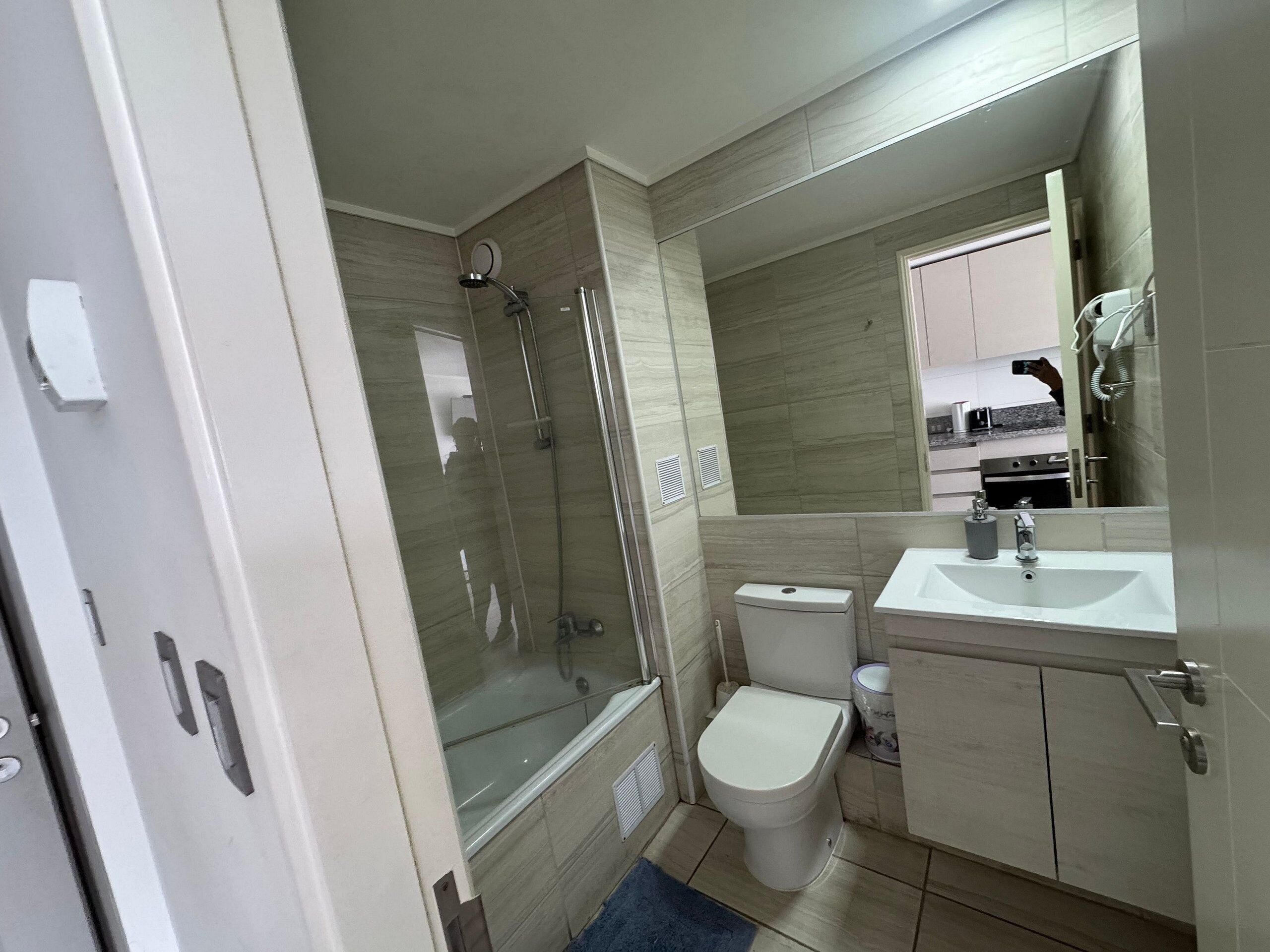 Un baño moderno con ducha envuelta en vidrio, inodoro y lavabo.