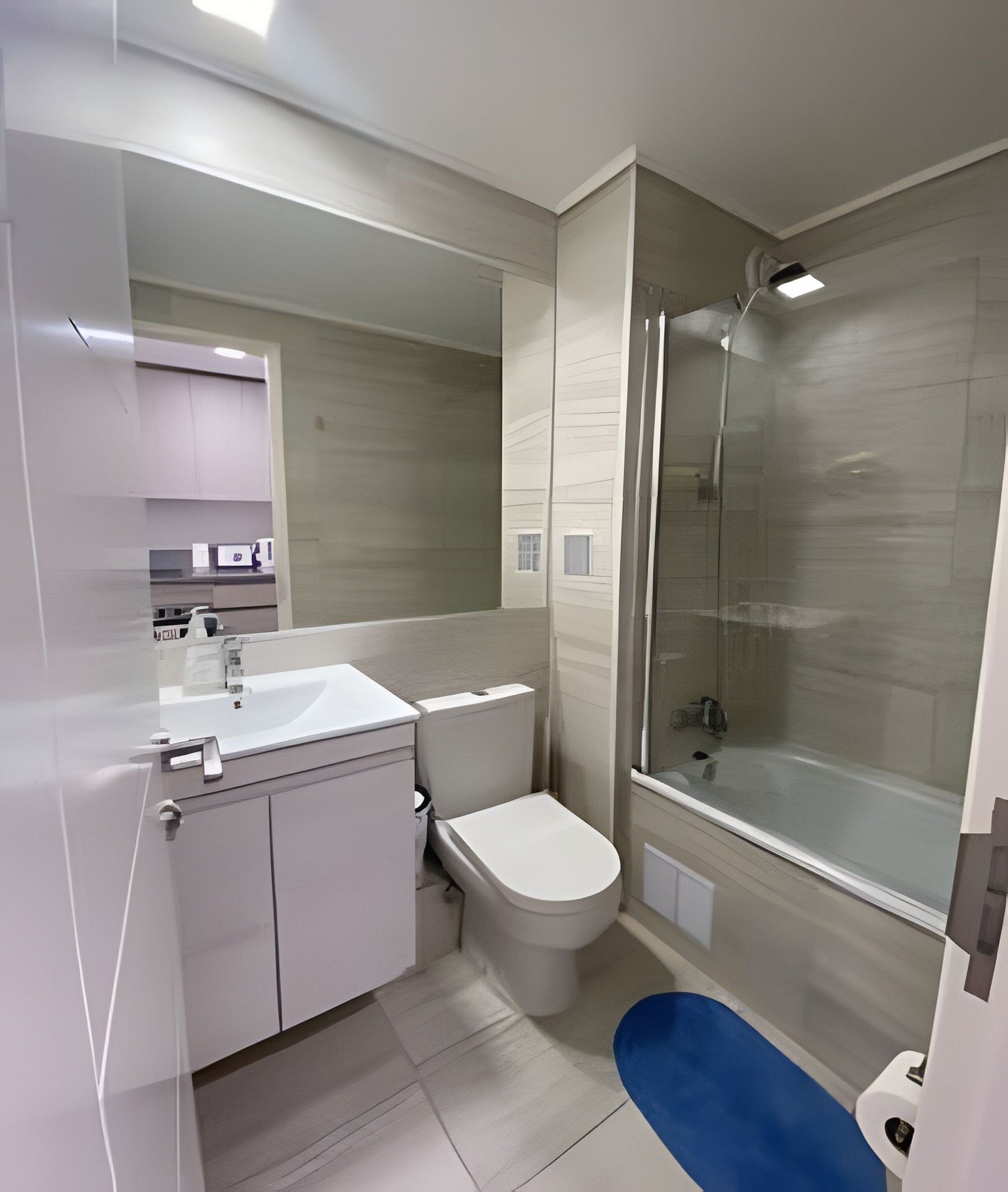 Un baño moderno con cabina de ducha de vidrio, inodoro blanco y lavamanos con espejo.