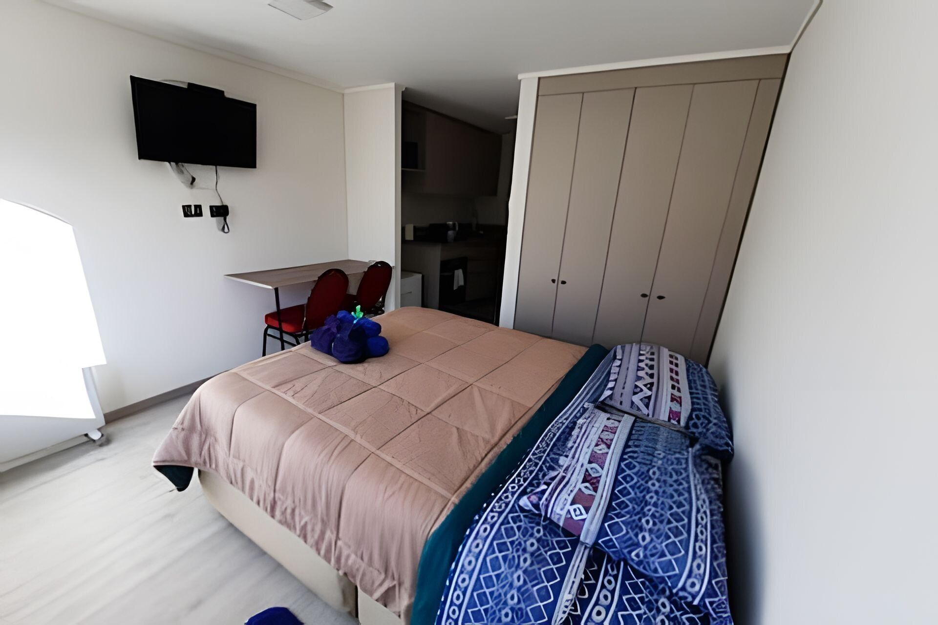 Un dormitorio con cama, escritorio y armario.