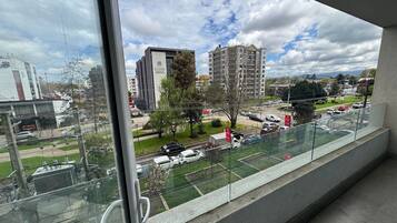Vista desde un balcón sobre un estacionamiento y edificios, incluyendo una estructura alta con un letrero.