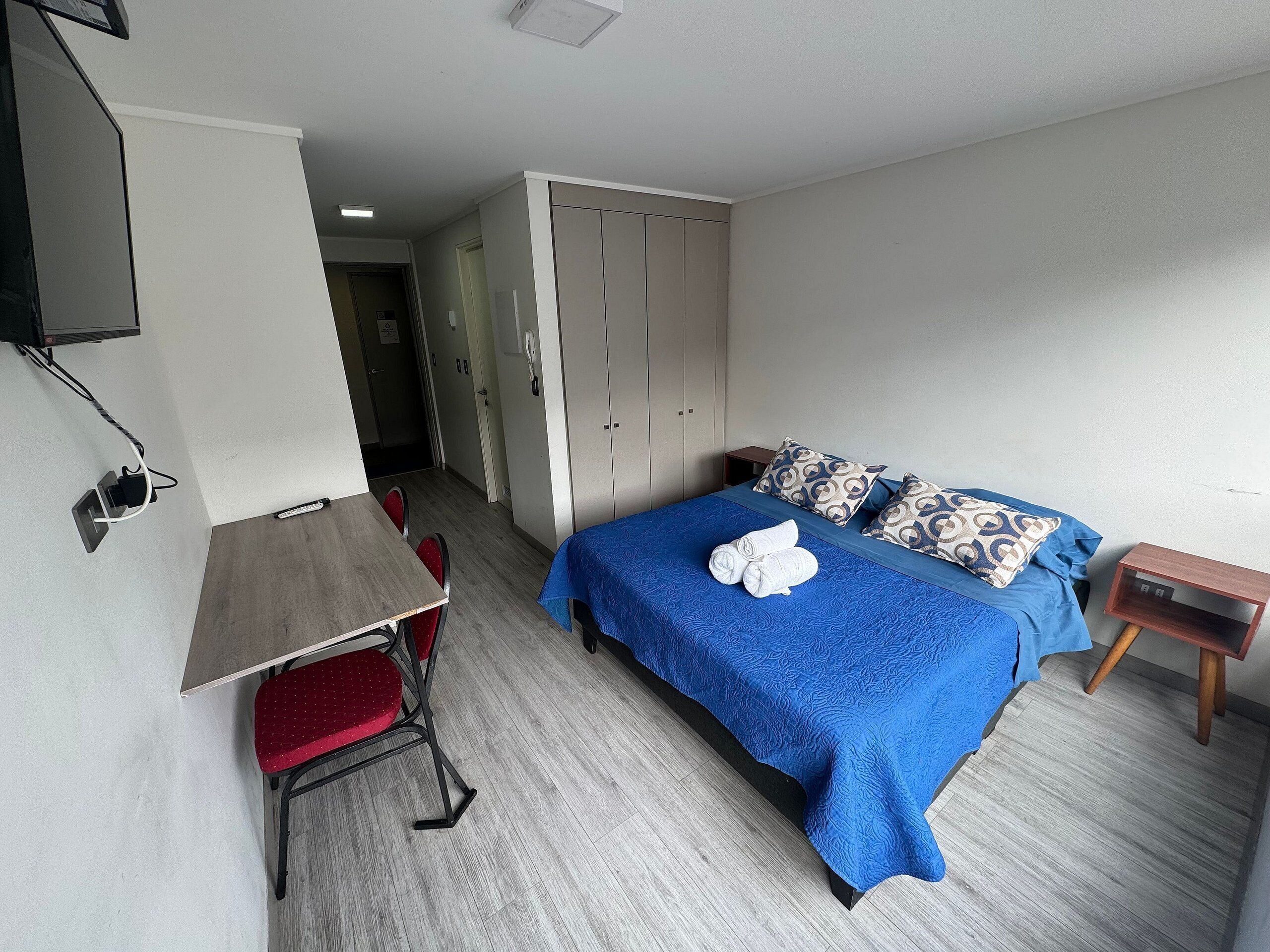 A hotel room with a bed, a desk, and a chair.