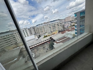 Vista desde una ventana que da a un paisaje urbano con edificios modernos, un campo deportivo y cielo despejado.