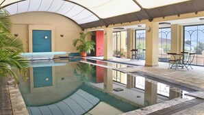 Une piscine intérieure offrant une vue dégagée sur les environs, avec notamment une porte, une chaise et une table.