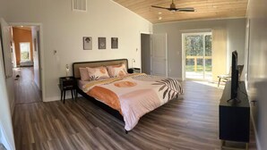 Quarto com uma cama grande, televisão e porta de vidro deslizante para uma varanda.
