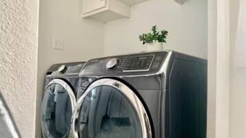 A front-loading washer and dryer in a laundry room with white cabinets above.