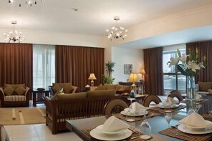 A hotel living room with a sofa set, dining table, and decorative items. - Marina Hotel Apartments (Dubai)