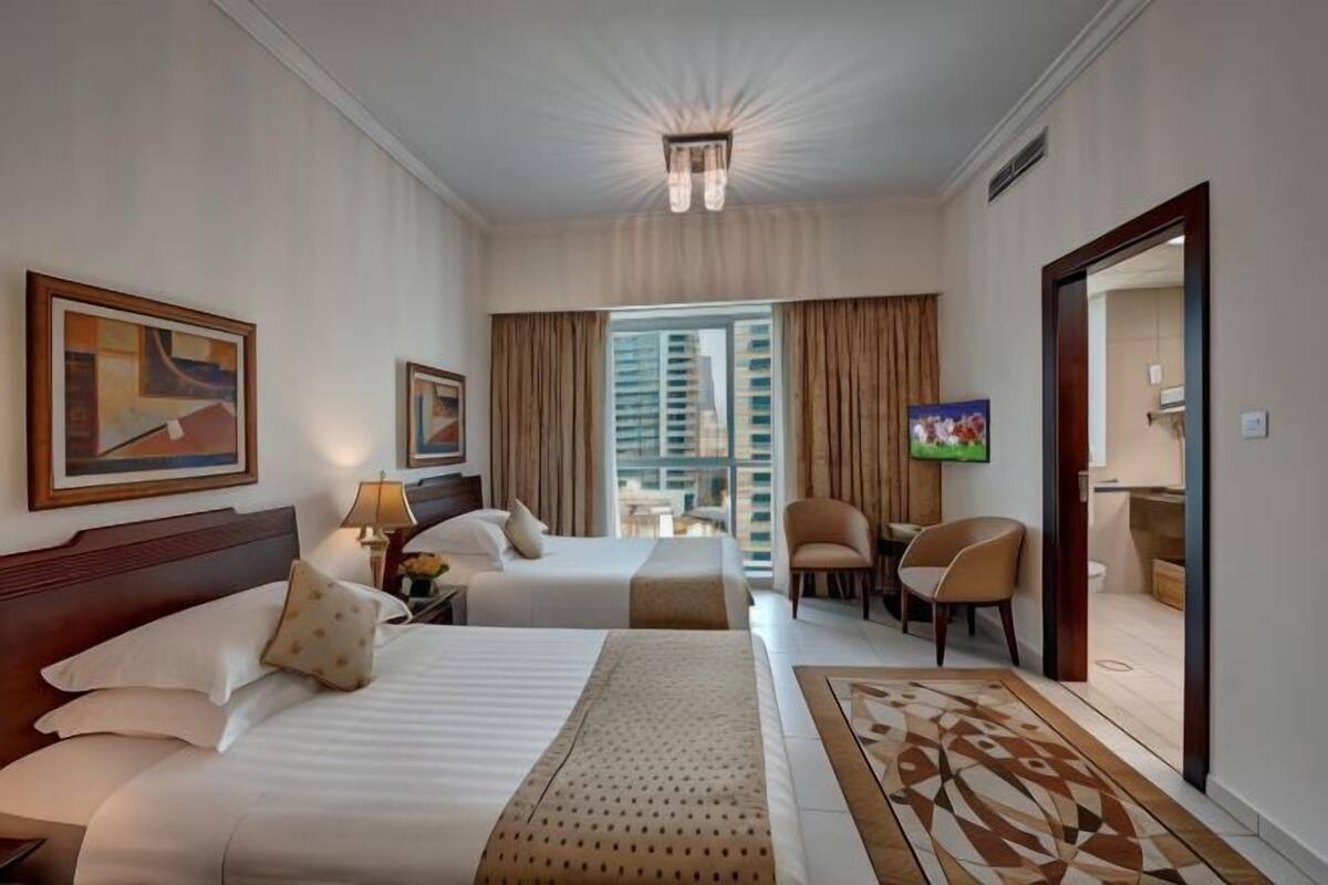 Une chambre d’hôtel avec deux lits, une télévision, un bureau et une chaise.