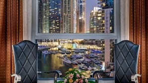 Una habitación con dos sillones de cuero negro orientados hacia una ventana con vistas a la ciudad.
