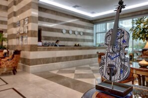 Un espace d’accueil comprenant un comptoir de réception, des chaises et une sculpture décorative en forme de guitare.