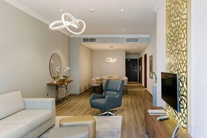 A modern living room with a sofa, armchair, and a flat-screen TV mounted on the wall. - Marina Hotel Apartments (Dubai)