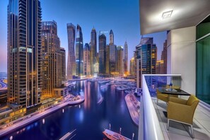Une chambre d’hôtel moderne avec vue sur la ville, un balcon doté d’un espace repas et une grande fenêtre.