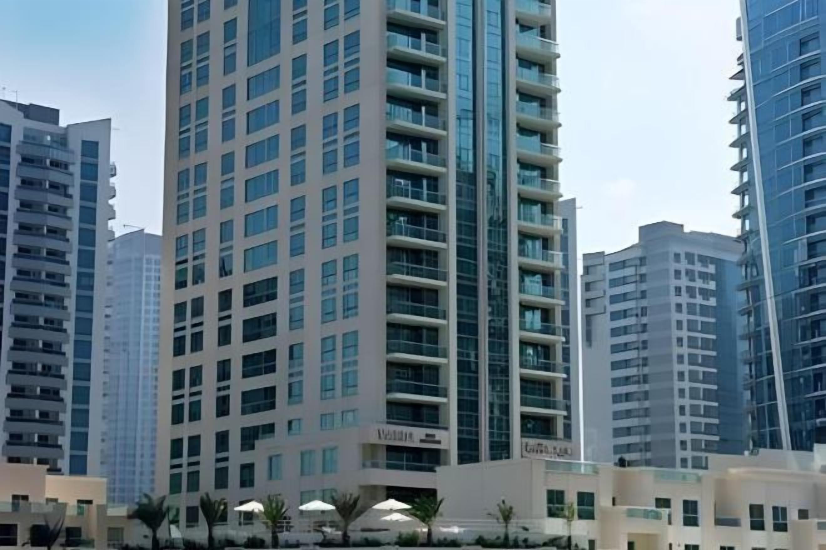 A high-rise building with multiple floors, balconies, and a clear sky.