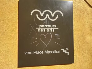A sign with the text 'parcours des arts' and 'vers Place Massillon' on a brown background.