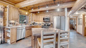 Une cuisine spacieuse dotée de meubles en bois, d’appareils électroménagers en acier inoxydable et d’un îlot central avec des sièges.