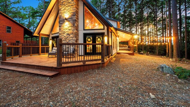 Een chalet met een stenen gevel, een terras en een veranda met zitplaatsen.