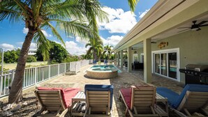 A poolside area with lounge chairs, a pool, and a grill. - CUDJOE GARDENS SANCTUARY- 3 BED/ 2 BATH- POOL, SPA, RV HOOK UP, BRING YOUR BOAT (Cudjoe Key)
