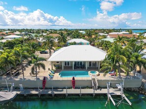 A beachfront property with a swimming pool, palm trees, and a view of the ocean.