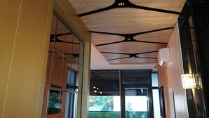 Um interior moderno com teto de madeira com padrões geométricos e iluminação embutida.