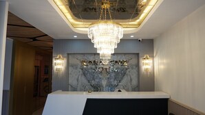 Uma receção com candelabro, parede de mármore e placa com o nome 'Karaden Hotel'.