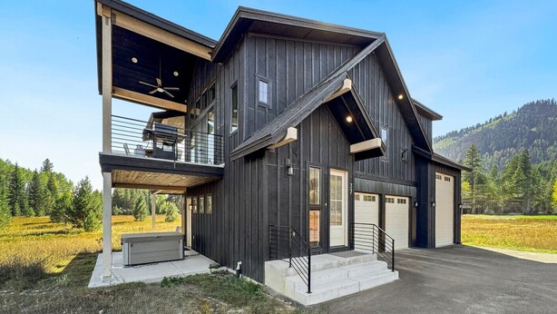 Een modern huis met twee verdiepingen, een grote garage, een balkon en een overdekt terras.
