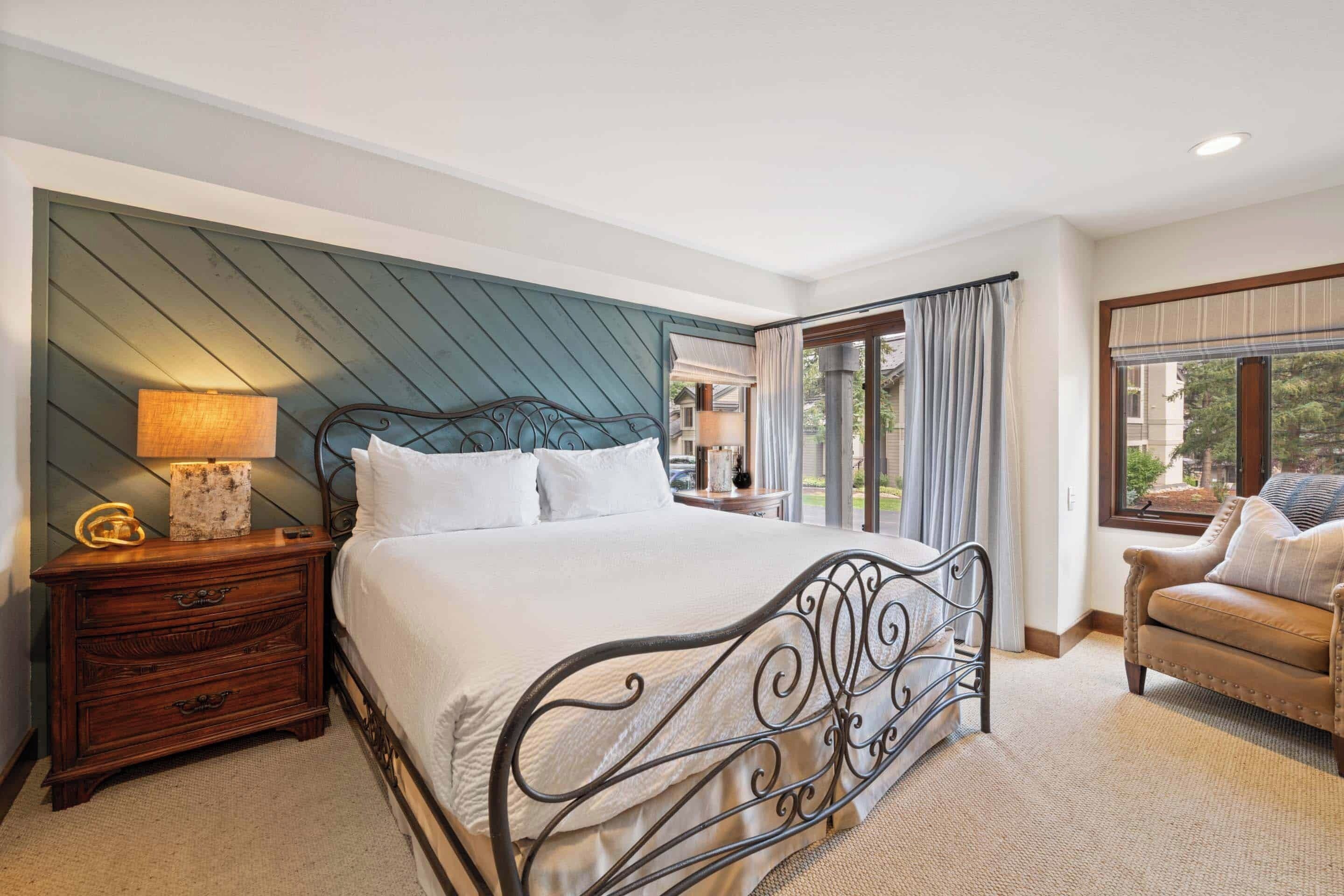 A bedroom with a bed, nightstand, and a view of the outdoors.