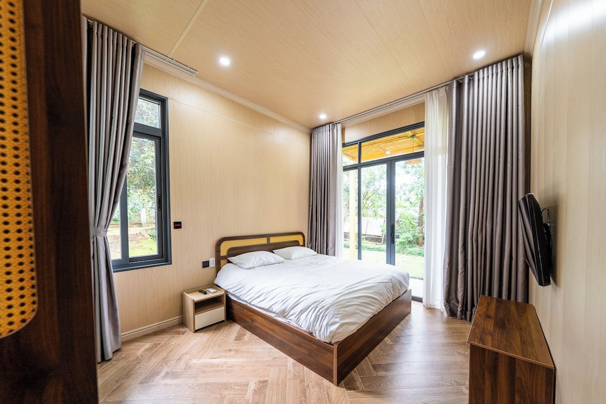 A modern bedroom with a wooden bed, a nightstand, and a TV mounted on the wall.