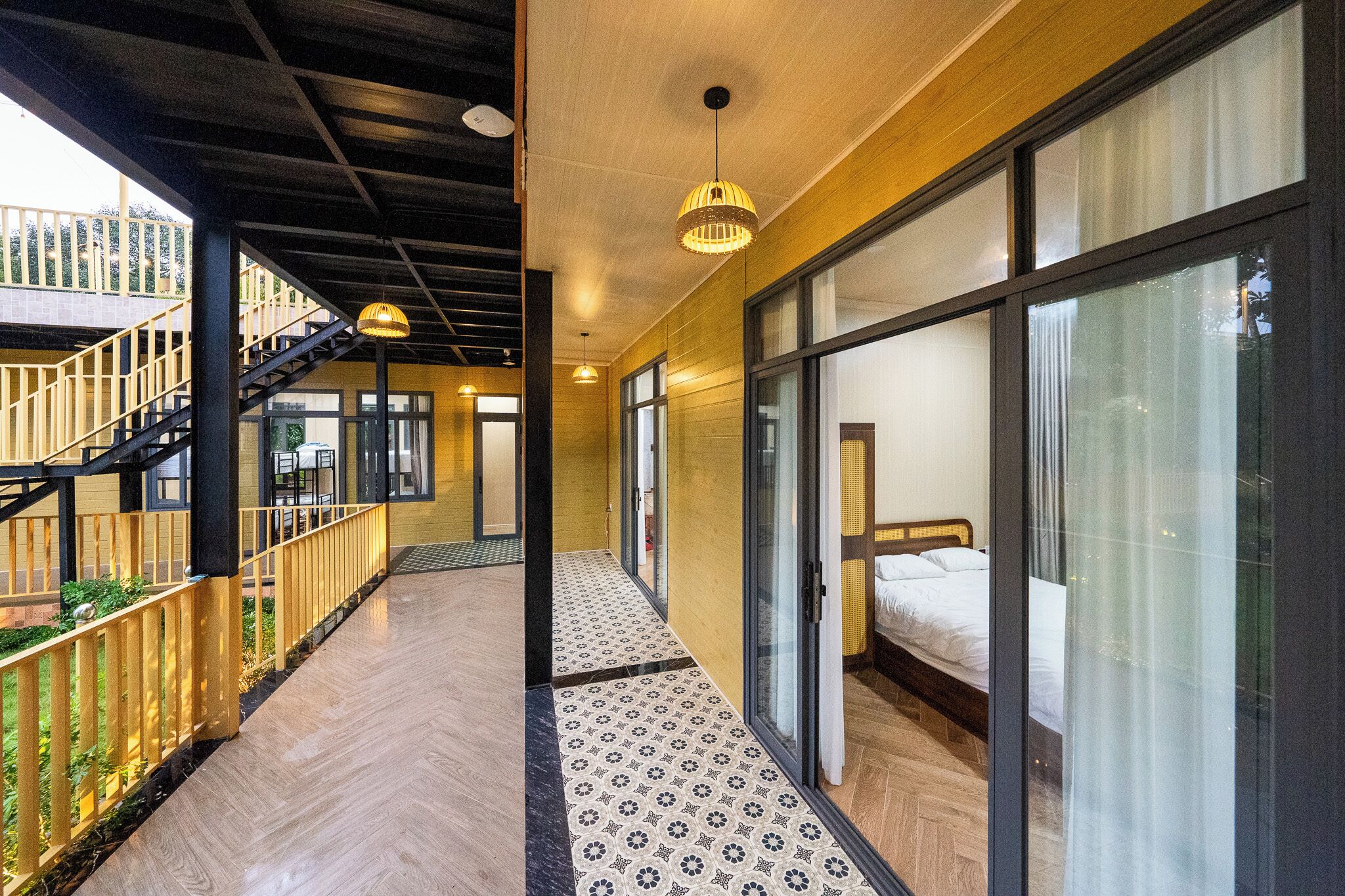 A modern hotel corridor with a wooden floor, a staircase, and a bed with a white duvet.