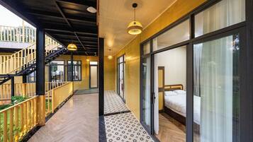A modern hotel corridor with a wooden floor, a staircase, and a bed with a white duvet.