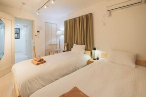 A hotel room with two beds, a desk, a chair, a lamp, and a curtain. - Calm Riverside Inn/Close to Ikebukuro (Tokyo)