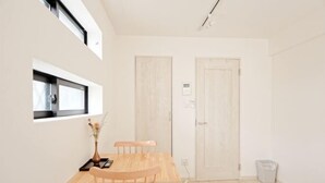A small, bright room with a wooden table and chairs, a window, and two doors. - Calm Riverside Inn/Close to Ikebukuro (Tokyo)