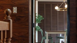 A wooden interior with a dining area, a hanging light fixture, and a visible door leading to another room. - Ikkenyahotel FUKUOKA (Fukuoka)