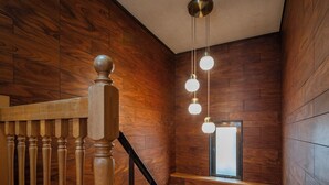 A wooden staircase with a black railing, a wooden handrail, and a window with a view of the outside. - Ikkenyahotel FUKUOKA (Fukuoka)