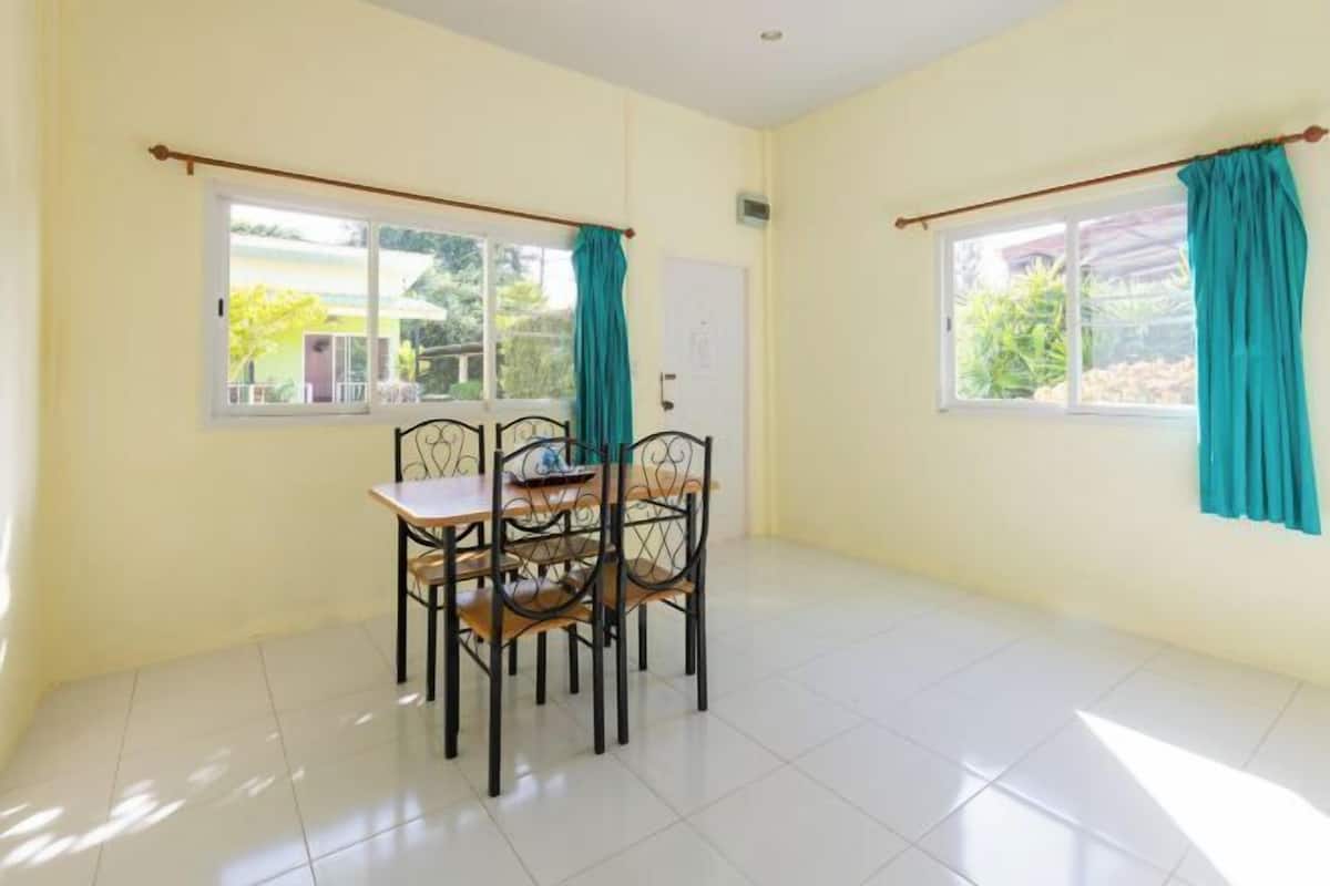 A room with a dining table and chairs, a window with curtains, and a white door.