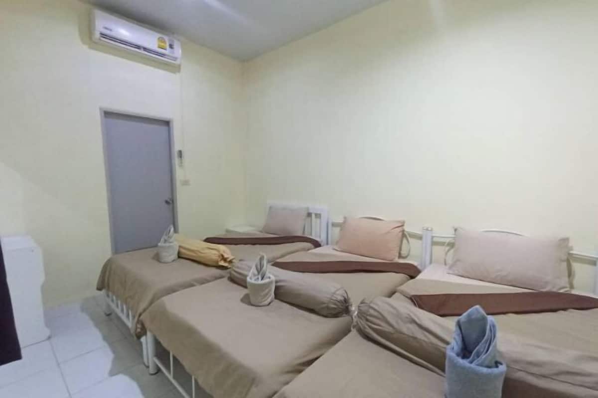 A room with three beds, a door, an air conditioning unit, and a white radiator.