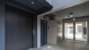 A modern hotel lobby with a glass door entrance, a staircase, and a ceiling with recessed lighting. - Sumida DIAS (Tokyo)