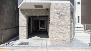 An entrance with a stone facade, a covered walkway, and a metal door. - Sumida DIAS (Tokyo)