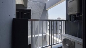 A room with a view of the city, a window air conditioner, and a metal railing. - Sumida DIAS (Tokyo)