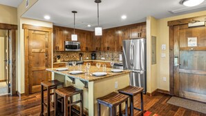 A modern kitchen with wooden cabinets, stainless steel appliances, and a central island with bar stools.
