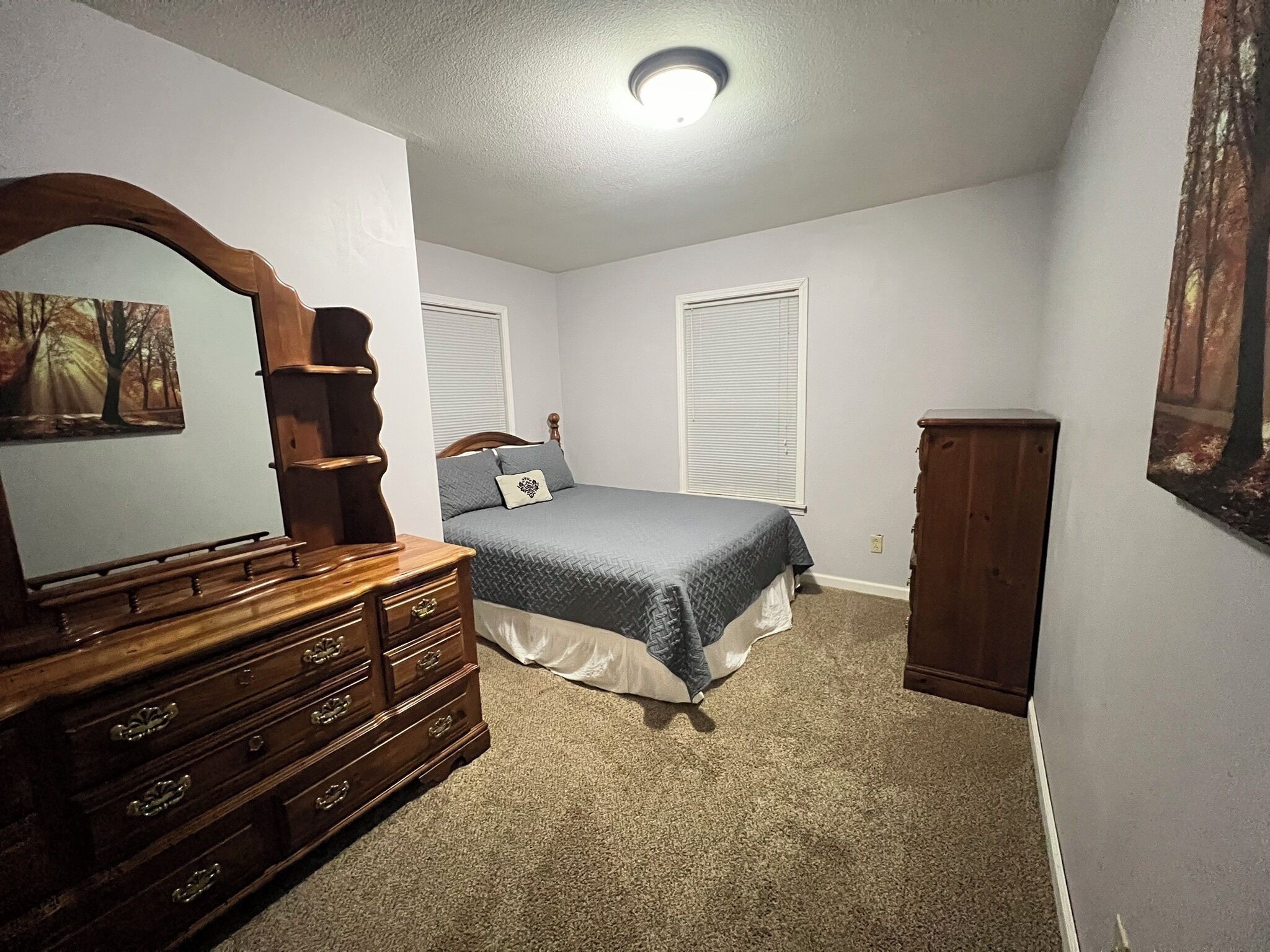 A bedroom with a bed, dresser, and a large mirror.