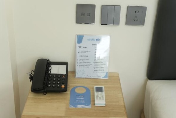 A hotel room with a bedside phone, a check-out form, a key card, and a power outlet on the wall. - LuckyTito Divers Boracay Island Resorts (Malay)