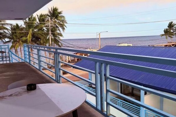 A balcony with a view of the sea and palm trees, a table, and a railing. - LuckyTito Divers Boracay Island Resorts (Malay)