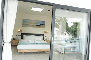 A bedroom with a bed, a painting, a nightstand, and a balcony with a railing. - LuckyTito Divers Boracay Island Resorts (Malay)