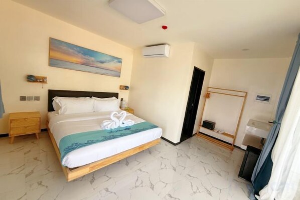 Une chambre d’hôtel comprenant un lit, un tableau, un appareil de climatisation, une table de chevet et une armoire.