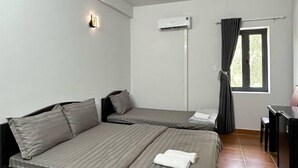 Une chambre avec deux lits, un bureau, un appareil de climatisation et une fenêtre avec des rideaux.