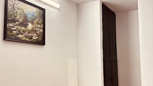 Une pièce avec un tableau encadré, une porte sombre et un interrupteur sur le mur.