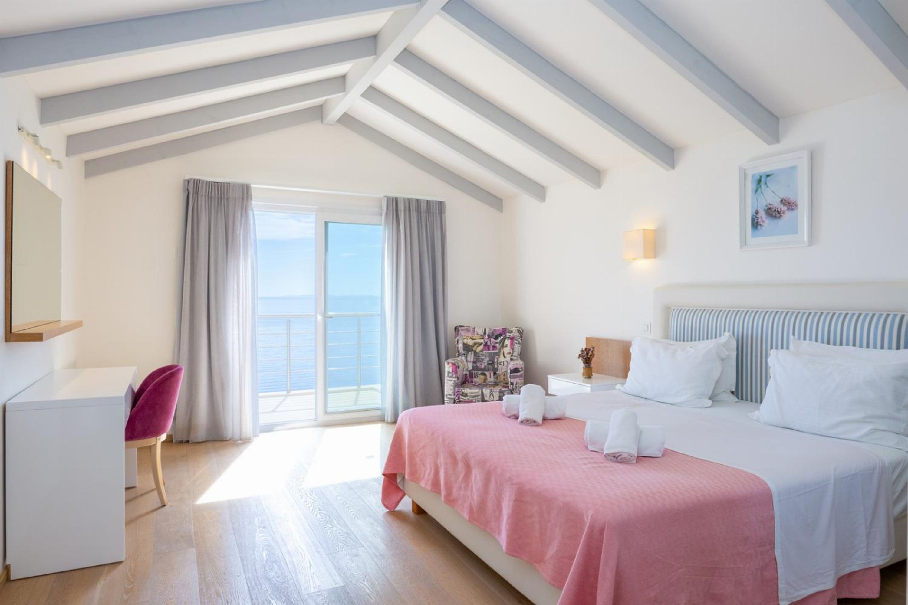 Une chambre à coucher avec un lit, un bureau, une chaise et une vue sur la mer.