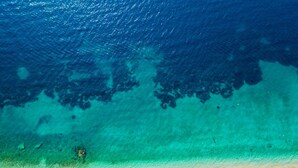 An aerial view of a beach with clear turquoise waters, a sandy shore, and rows of beach umbrellas and lounge chairs. - Villa Penelope With 4 Bedrooms and 3 Bathrooms (Corfu)