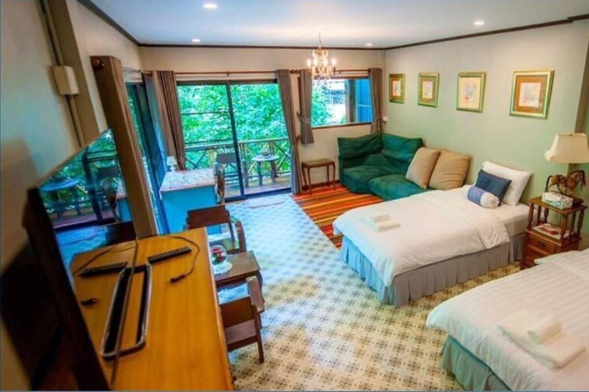 A hotel room with two beds, a dining area, a small table, and a view of the outdoors.