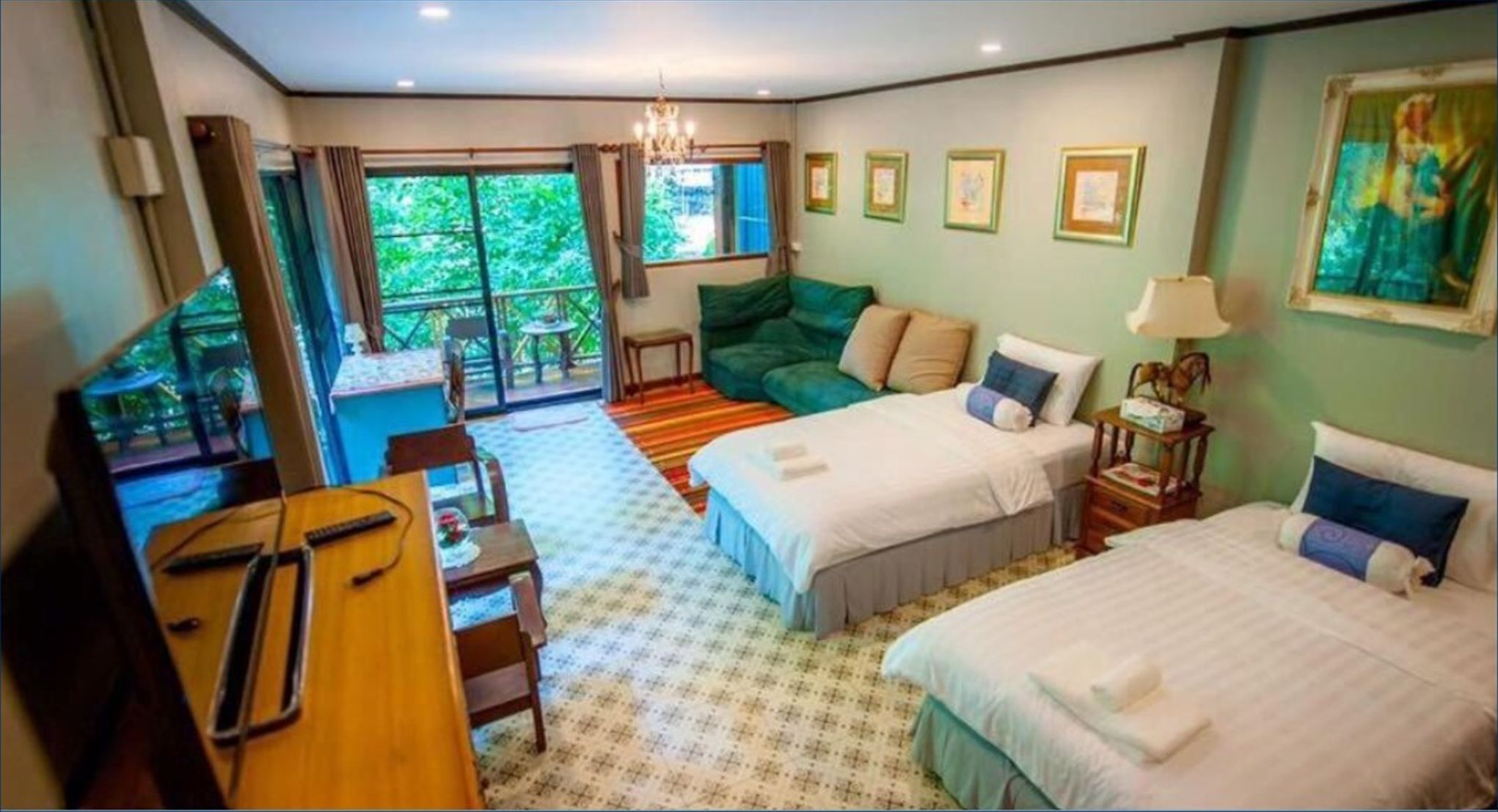 Een hotelkamer met twee bedden, een zithoek, een kleine tafel en uitzicht op het omliggende landschap.