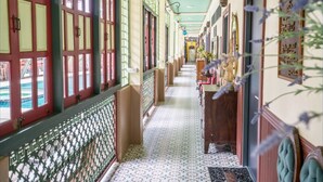 Ein Korridor mit gemustertem Bodenbelag, roten Fensterrahmen und einer grünen Decke.